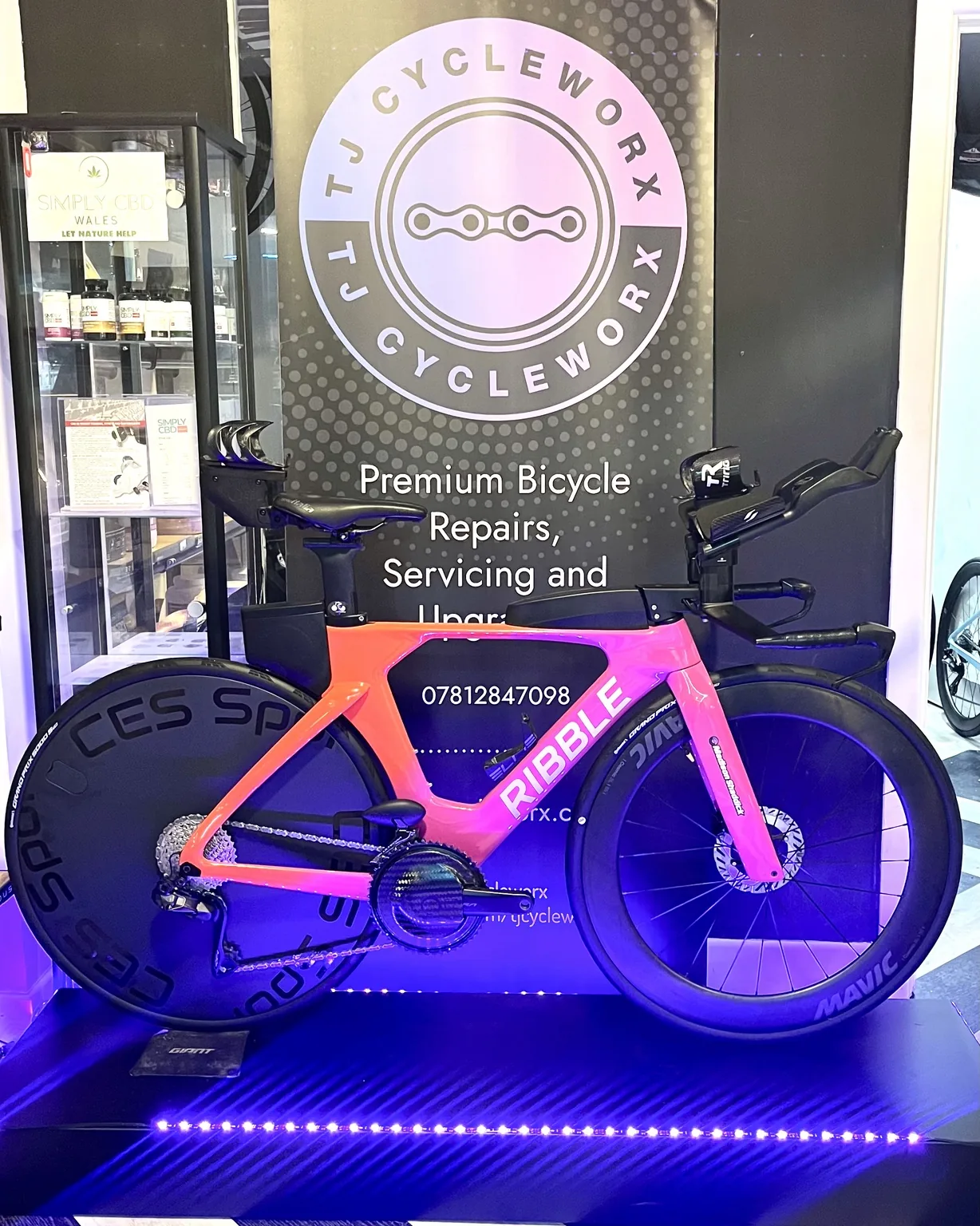 Pink performance bike in front of the TJ CycleWorx workshop sign